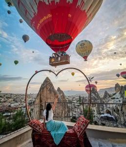 a woman sitting on a chair with hot air balloons at Elite Cave Suites in Göreme +82 photos