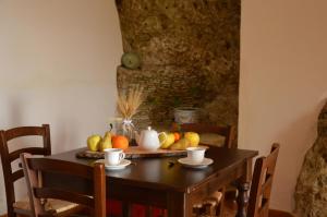 een houten tafel met fruit en kopjes erop bij Agriturismo Masseria La Chiusa in San Giuseppe Iato