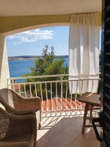 a balcony with chairs and a view of the water at Apartman Rosa 2 in Kustići