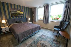 a bedroom with a bed and a chair and two windows at Ferienhaus mit Terrasse und Garten in Wandlitz in Wandlitz