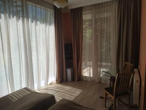 a bedroom with a bed and a chair and large windows at Nunisi Forest Hotel & SPA in Nunisi