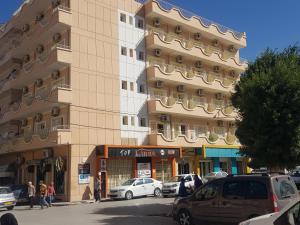 un gran edificio con coches estacionados frente a él en Hotel el Hayat en Batna