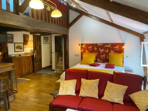a living room with a red couch and a bed at Le Relais Du Haras - Deauville in Touques