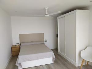 トレモリノスにあるCarihuela Beach Apartamentosの白いベッドルーム(ベッド1台、クローゼット付)