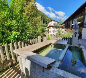 een zwembad met een bank en een houten hek bij Alla Curva di Elia Manzoni in Malè