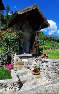uma pequena casa com uma parede de pedra e flores em Alla Curva di Elia Manzoni em Malè