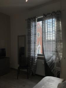 1 dormitorio con ventana con cortinas y silla en Cà Nicola 2, en Cortemaggiore