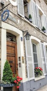 un bâtiment avec une porte et des fleurs devant lui dans l'établissement Royal Hubert, à Provins