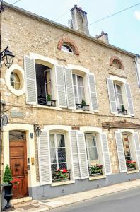 ein Gebäude mit weißen Fensterläden und Blumen in den Fenstern in der Unterkunft Royal Hubert in Provins