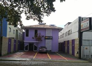 a purple building with a car parked in a parking lot at Pousada Vison in Ubatuba