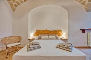 una camera da letto con un grande letto bianco con asciugamani di Corte Anibaldi Apartment a Lecce