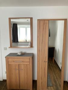 um quarto com um espelho, um armário de madeira e uma porta em Pension Zur Alten Post em Untermeitingen