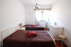 a bedroom with two beds and a dresser and a window at Foz Beach House in Buarcos