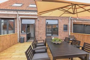 a patio with a wooden table and chairs and an umbrella at Royaal appartement in het centrum van Yerseke in Yerseke