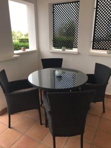 einen Tisch und Stühle in einem Zimmer mit zwei Fenstern in der Unterkunft Hacienda Riquelme Golf Resort, Atlantico 188, Ground Floor Apartment in Sucina