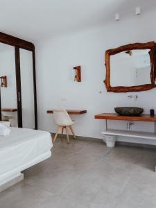 a bedroom with a bed and a sink and a mirror at Eternal Suites in Mikonos