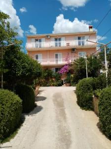 uma casa cor-de-rosa com uma varanda numa estrada de terra batida em Apartmani Nado Majica em Sveti Filip i Jakov