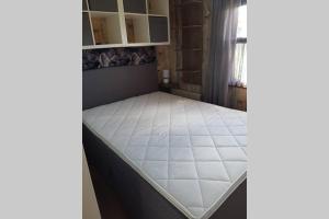 een bed in een kamer met een wit matras bij Stuyvesanthof scheldeoord chalet 710 in Baarland