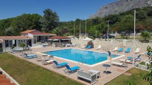 a large swimming pool with chairs and a house at KOSTA MARIA in Paleros