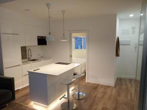 a white kitchen with a counter and stools at Triana Parque VV in Las Palmas de Gran Canaria