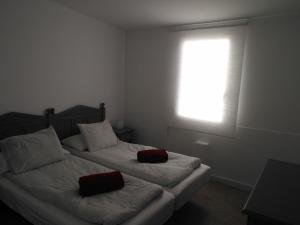 a bedroom with two beds with red pillows and a window at Apartamentos Rocamar el Medano in El Médano