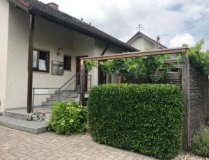 una casa con un seto delante de un edificio en Ferienwohnung im sonnigen Kaiserstuhl, en Endingen am Kaiserstuhl