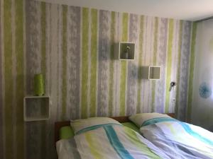 um quarto com uma cama com riscas verdes e brancas em Ferienwohnung im sonnigen Kaiserstuhl em Endingen