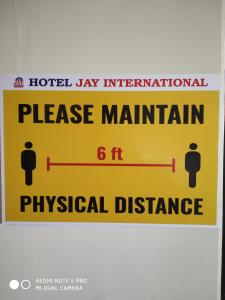 ein Schild an einer Wand, auf dem steht, bitte halten Sie Abstand. in der Unterkunft Hotel Jay International in Vapi