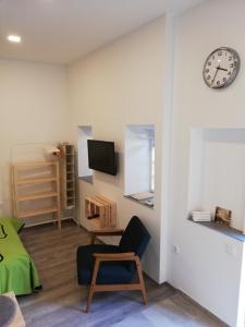 a room with a chair and a clock on a wall at Studio apartman Fleiss in Samobor