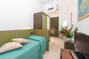 een slaapkamer met een groen bed en een televisie bij Hotel Sirena in Lido di Camaiore