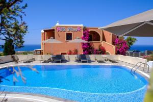 a pool with chairs and umbrellas in front of a building at Pension The Flower in Oia