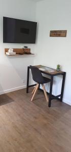 a table with a chair and a television on a wall at Concept Appart'Hôtel Lannion - Côte de Granit Rose in Lannion