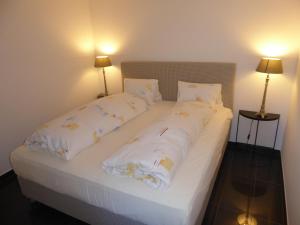 łóżko z białą pościelą i poduszkami w obiekcie Rheinblick Résidence w mieście Tägerwilen