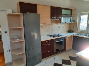a kitchen with a stainless steel refrigerator and wooden cabinets at Apartman Martina in Rab