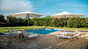 a patio with two umbrellas and chairs and a pool at Village Villas in Lygia