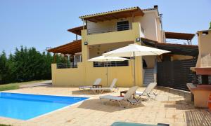 uma casa com piscina, cadeiras e guarda-sol em Village Villas em Lygia