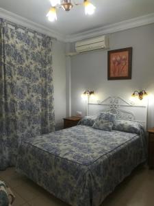 1 dormitorio con 1 cama y 2 lámparas y cortinas en Hostal Virgen Del Rocio, en Los Palacios y Villafranca