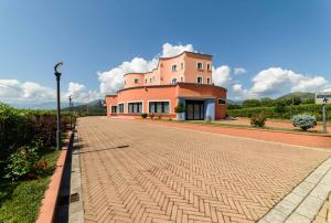 a large pink building on a brick road at Hotel Hermitage in Polla