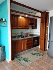 uma cozinha com armários de madeira e um lavatório em Nautilus I: Casa con terraza y vistas al mar em La Caleta
