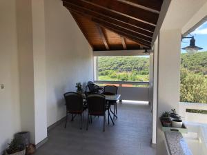 a patio with a table and chairs and a large window at Apartmani Ankica in Kampor