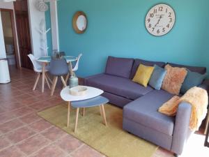 a living room with a purple couch and a clock on the wall at Nautilus I: Casa con terraza y vistas al mar in La Caleta