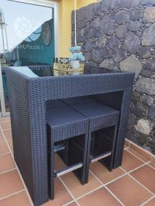 a black wicker table and two stools on a patio at Nautilus I: Casa con terraza y vistas al mar in La Caleta