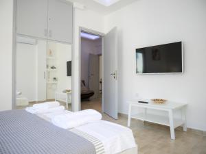 biała sypialnia z 2 łóżkami i telewizorem w obiekcie Lux Sea Apartment - Porto Rafti w mieście Porto Rafti