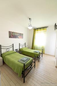two beds in a room with green sheets at B&B Casa Fortuna in Lecco