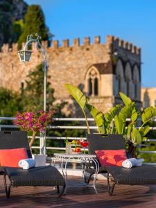 a patio with two chairs and a table and a building at Hotel Continental in Taormina