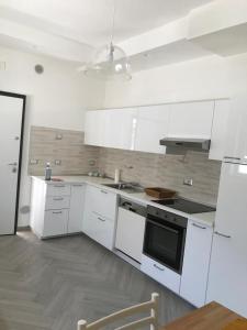 a kitchen with white cabinets and a stove top oven at Appartamento in Villa in Ginosa Marina