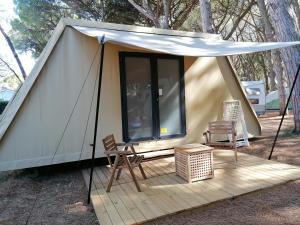 Tenda con tavolo e sedie su una terrazza in legno di Camping Village Oasi ad Albinia