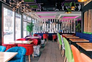 un restaurant avec des chaises, des tables et des fenêtres colorées dans l'établissement ESTRADA Lux, à Belgrade