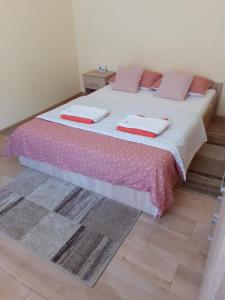een slaapkamer met een bed met roze lakens en kussens bij Apartament Andreas in Arad