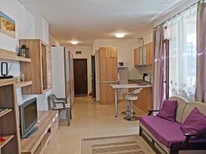ein Wohnzimmer mit einem lila Sofa und einer Küche in der Unterkunft Светлая новая студия в Приморско in Primorsko